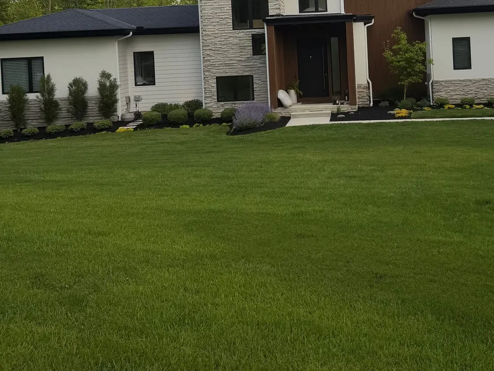Foundation planting beds with clipped shrubs, flowering perennials, fresh mulch, and a crisp cut edge